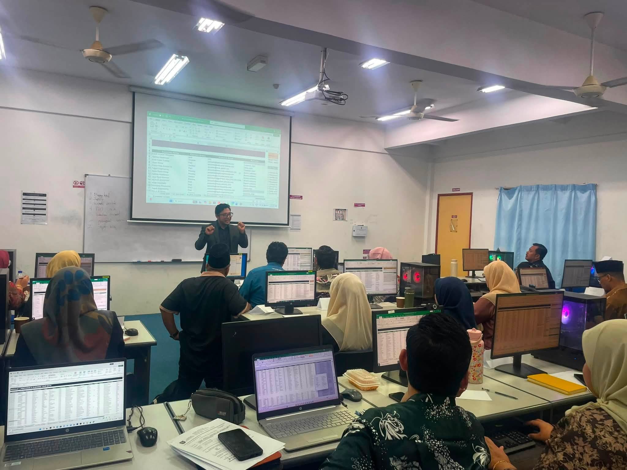Trainer presenting to participants in a computer-equipped classroom
